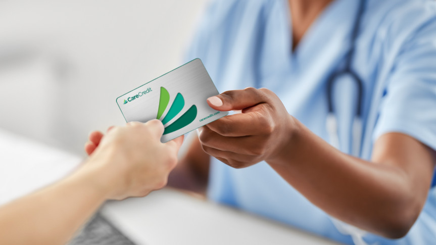 person handing over carecredit card to nurse