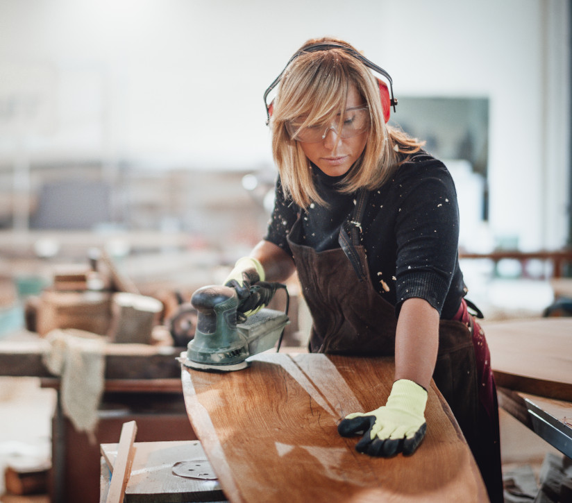 Woman carpenter sanding a table